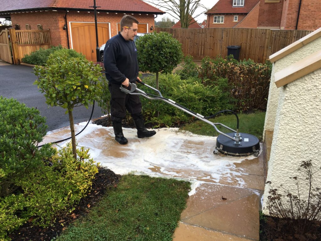 A professional cleaner in Leighton Buzzard pressure washing a pathway with a softwashing technique, effectively removing dirt and grime.