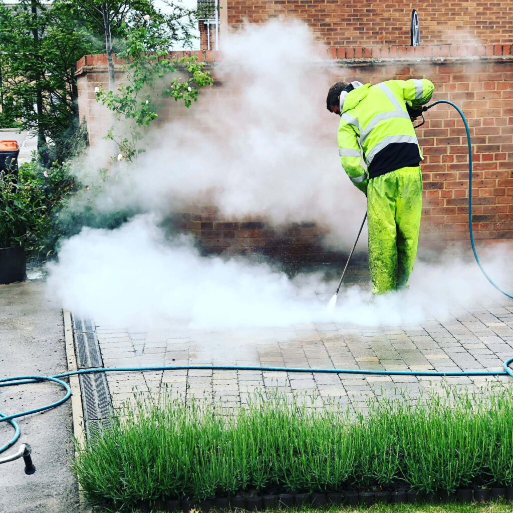 A man pressure washing a block paving drive.